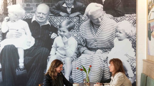 Women in Landemare cafe, Chartwell in front of a huge black and white family photo featuring Winston Churchill